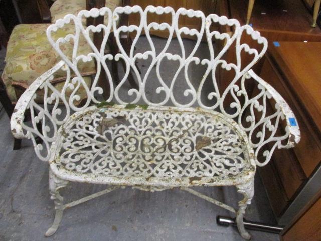A weathered cast iron garden bench with scrolled ornament, on cabriole legs