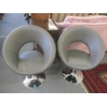A pair of modern leather upholstered swivel chairs on chrome circular bases