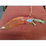 A Kukri with a painted handle and a red leather sheath