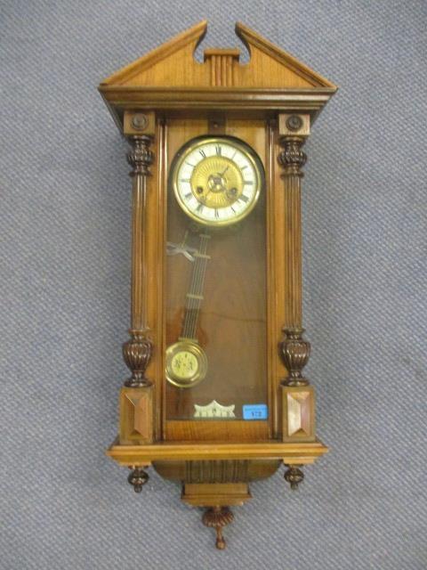 A Victorian walnut cased Vienna wall clock of architectural design and having an enamel dial with