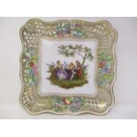 A Dresden dish with pierced and floral sides, the central panel decorated with a man playing a