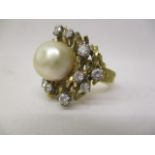 A gold coloured ring set with a central pearl, approximately 11mm, surrounded by twelve irregular