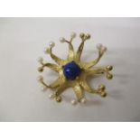 An 18ct gold flower design brooch, set with a Lapis Lazuli cabochon, in an open framework, gold