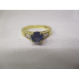 An 18ct gold ring set with a tanzanite 0.94ct, flanked by a pair of baguette cut diamonds, size L,