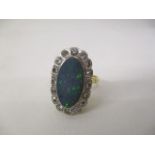 An 18ct gold ring set with an opal, approximately 15mm x 7mm within a border of thirteen diamonds,