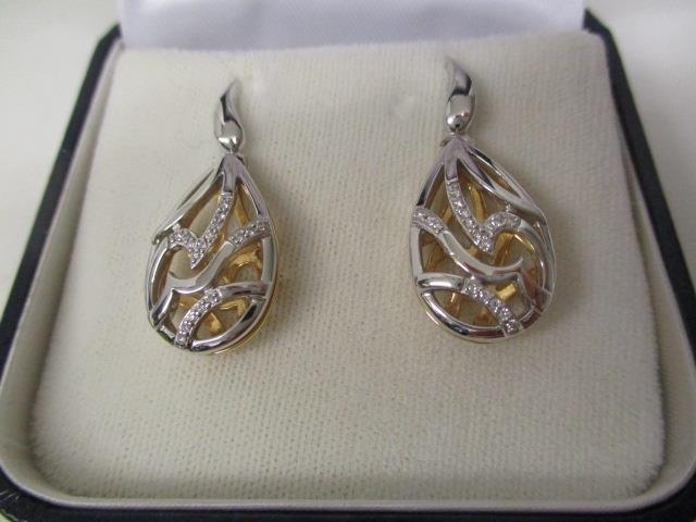 A pair of 18ct yellow and white gold earrings of drop design, with pierced decoration, set with