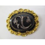 A mid Victorian gold coloured and black enamelled mourning brooch/pendant with a central domed