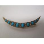 A gold coloured metal, crescent shaped brooch set with nine graduated turquoise cabochons and