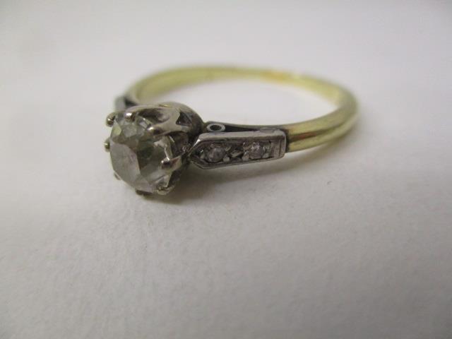 A gold and platinum coloured ring set with an oval diamond, approximately 0.65ct with four