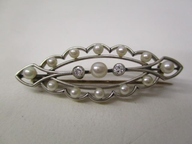 A gold and white coloured metal brooch of oval lobed form, set with thirteen pearls and two diamonds