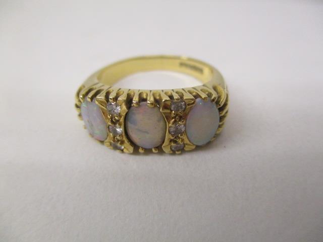 An 18ct gold ring set with three opals and six diamonds in a claw setting, with engraved