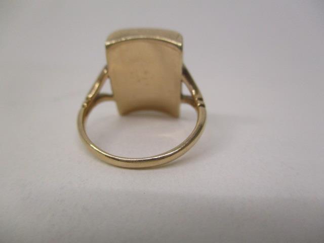 A gold coloured ring set with a central diamond on a black curved tablet and panelled back, size - Image 3 of 3