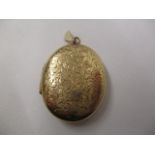 A 9ct gold oval locket with flowers engraved to the front, on a suspension ring, 9g