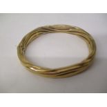 A gold coloured metal bangle with rope twist style ornament, stamped 9kt, 22.2g total