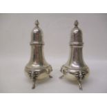 A pair of mid 20th century sterling silver pepper pots with acorn finials and tapered, bulbous