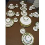 A Spode dinner service with a white background having an emerald and gold coloured rim and the