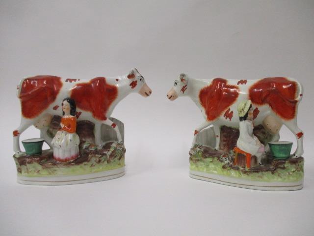 A pair of Victorian Staffordshire pottery flatback models of a boy and a girl each milking a cow,