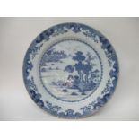 A late 18th century Chinese blue and white charger decorated with a river scene, boats, buildings