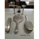 A selection of silver items to include a silver dressing table hand mirror, two silver bushes (one