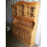 A modern pine dresser having glazed cupboard doors above three drawers and panelled doors, on a