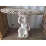 A stoneware garden circular topped table, the base in the form of a seated cherub, 31" h x 34 1/2"w