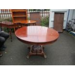 A reproduction mahogany circular extending dining table having two extra leaves, standing on paw