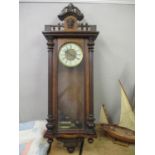 A late 19th century walnut Vienna style clock with carved ornament and an enamelled Roman dial