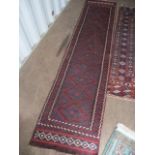 A Middle Eastern red ground runner having multiguard borders and tasselled ends, 110" x 25"