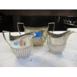 A silver sugar bowl with matching two cream jugs