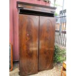 An early 20th century mahogany two door wardrobe having a dental moulded cornice on a plinth base,