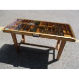 A mid 20th century display coffee table with inset printing blocks and tools