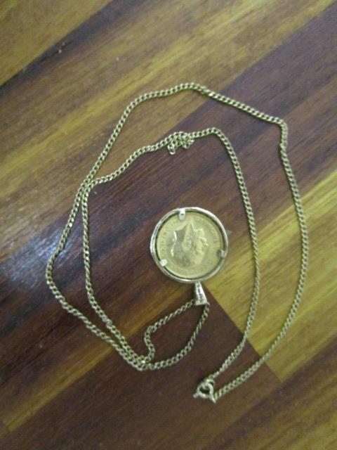 A George V 1914 gold half sovereign set in a 9ct gold setting and on a 9ct gold chain necklace,