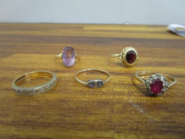 A group of 9ct gold and gem set rings to include a garnet ring and an amethyst ring, along with a