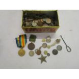 A vintage tin containing various coins to include a 1913 two-shilling coin, an ARP silver badge, a