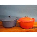 A blue Le Creuset casserole dish with lid, and a similar one in burnt orange