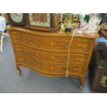 A reproduction yew serpentine fronted French style chest with three long drawers