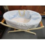 A Moses basket with a blue fabric lining on a painted folding stand