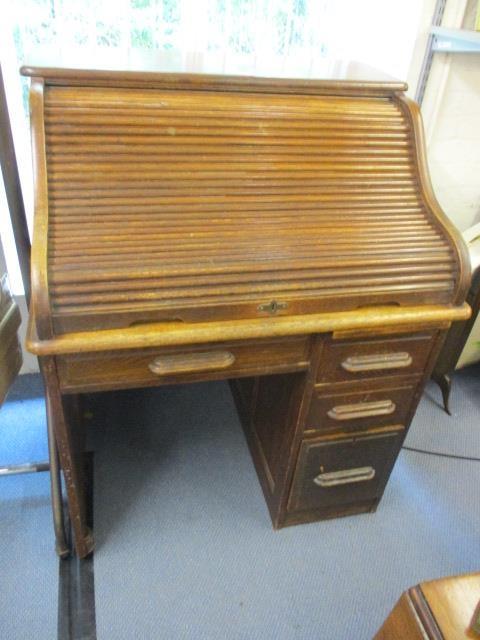 An early 20th century oak roll top desk having fitted compartments above one long, single drawer and