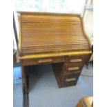 An early 20th century oak roll top desk having fitted compartments above one long, single drawer and