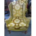 A reproduction Georgian style wing back chair with scrolled arms, carved, cabriole front legs with