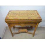 An early 20th century bone/ivory and mixed veneered marquetry games table, with a rotating