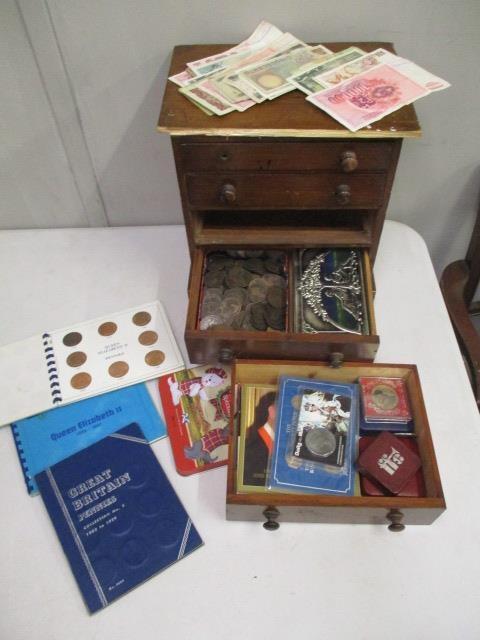 A stained pine four drawer chest containing various coins sets, banknotes, foreign coins and