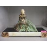 An Art Deco painted spelter figurine of a seated lady reading a book with a dog by her side, mounted