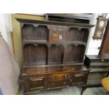 An early 20th century oak dresser, the top with central glazed display door over open shelves with