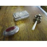 A small silver pill box, a white metal child's rattle with mother of pearl handle, and a silver oval