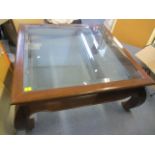 A modern mahogany finished large glass topped coffee table 16 1/2"h x 40 1/2"w