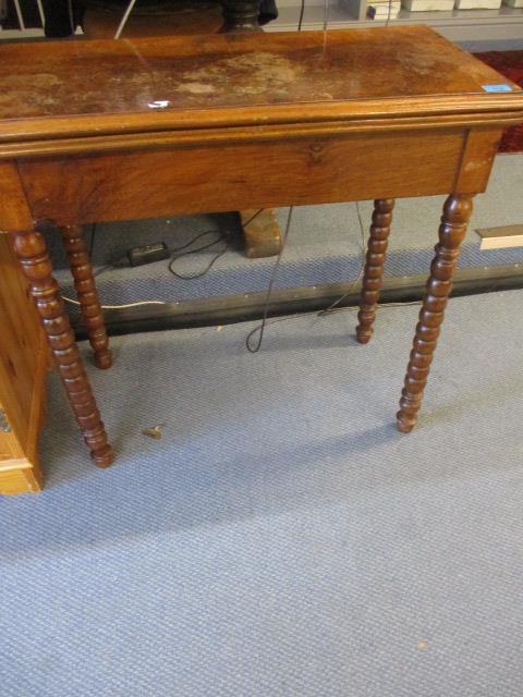 A 19th century walnut card table with a rotating, fold over top on bobbin turned legs