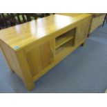 A modern oak cabinet with two shelves flanked by a pair of doors, on rectangular legs