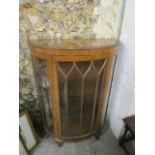 An art deco walnut bow fronted display cabinet with arched glazed display door, on carved short