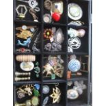 A modern jewellery display case containing vintage brooches and pin badges to include enamelled